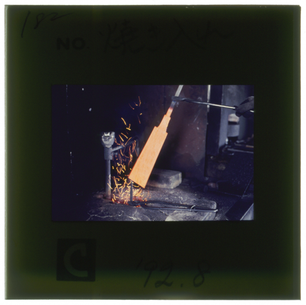 焼入れ作業。ガス炉で溶かした鉛(800℃前後)に鋸身を入れて加熱してから,手早く油槽に浸して急冷する。脇野町鋸工業組合の組合...